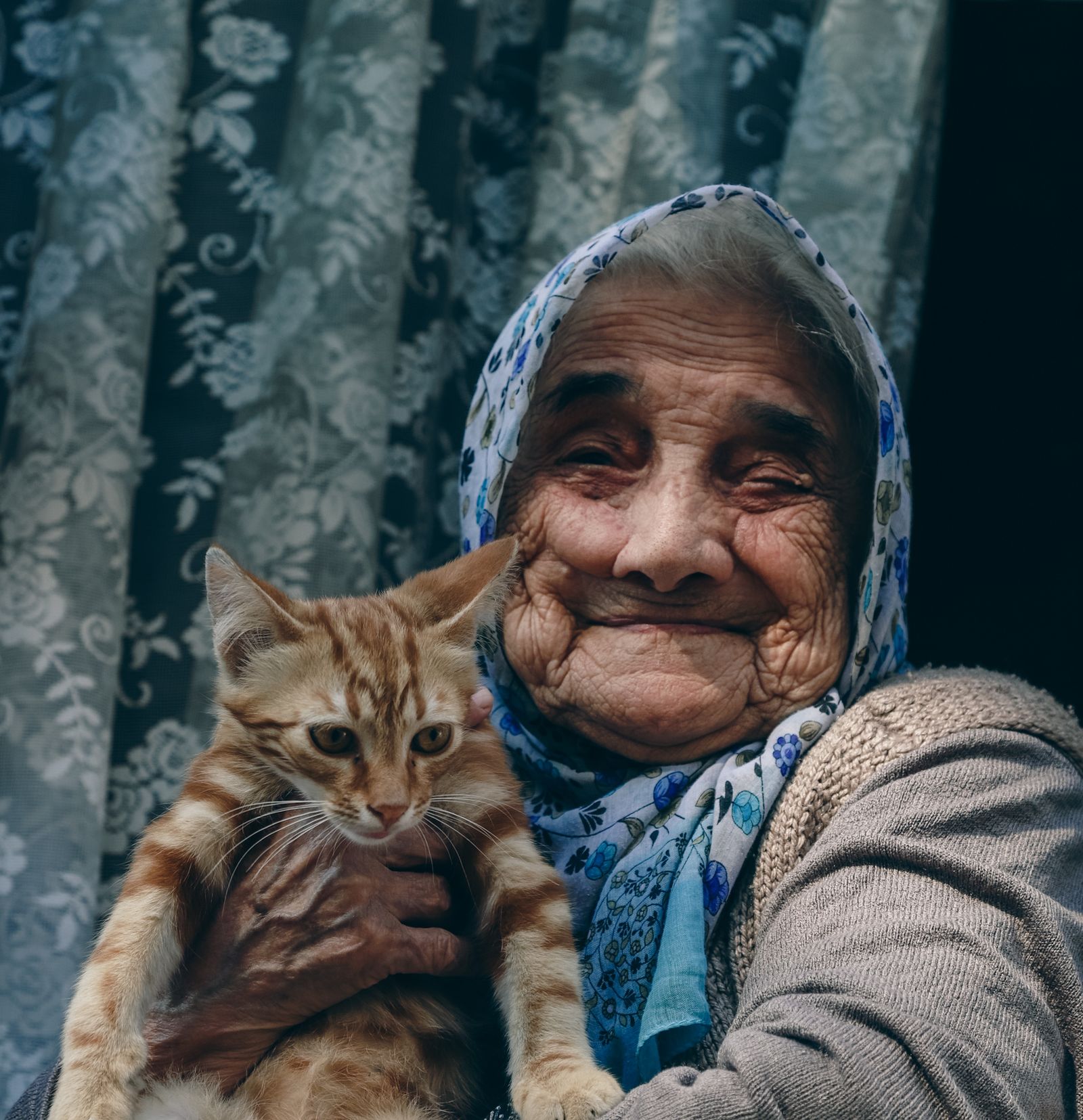 Une femme âgée sourit en tenant son chat tigré
